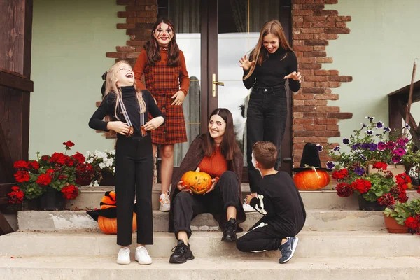 I bambini felici festeggiano Halloween per strada vicino alla casa in costume e trucco con jack per lanterna di zucca, guardando la fotocamera e divertendosi — Foto Stock