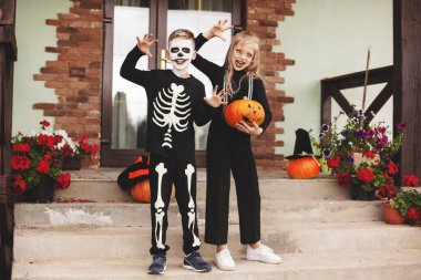 Mutlu çocuklar Cadılar Bayramı 'nı evin yakınındaki cadılar bayramında kostümlü, balkabağı fenerli Jack' le makyaj yaparak kameraya bakarak ve eğlenerek kutluyorlar.