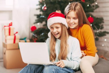 Sarışın, Avrupalı görünümlü iki mutlu genç kız kardeş Noel günü arkadaşları ve büyükbabalarıyla bilgisayar bağlantısı yoluyla iletişim kuruyor. Yeni Yıl Arifesinde Sosyal Mesafe.