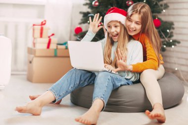 Sarışın, Avrupalı görünümlü iki mutlu genç kız kardeş Noel günü arkadaşları ve büyükbabalarıyla bilgisayar bağlantısı yoluyla iletişim kuruyor. Yeni Yıl Arifesinde Sosyal Mesafe.