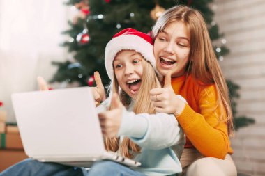 Sarışın, Avrupalı görünümlü iki mutlu genç kız kardeş Noel günü arkadaşları ve büyükbabalarıyla bilgisayar bağlantısı yoluyla iletişim kuruyor. Yeni Yıl Arifesinde Sosyal Mesafe.