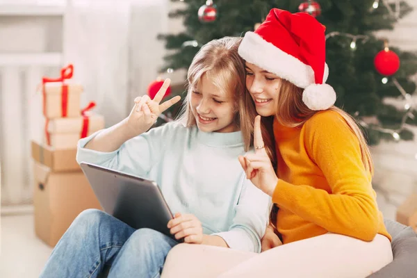 Dos adolescentes con rubias europeas se ve chat con amigos y abuelos en el día de Navidad. Distanciamiento social en la víspera de Año Nuevo. —  Fotos de Stock