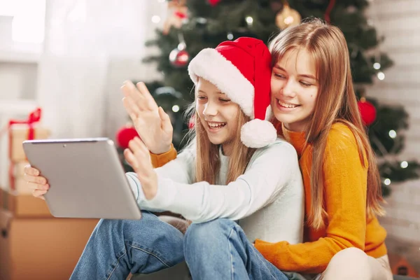 Due ragazze adolescenti con biondo europeo guarda chat con amici e nonni il giorno di Natale. Distanze sociali durante la vigilia di Capodanno. — Foto Stock