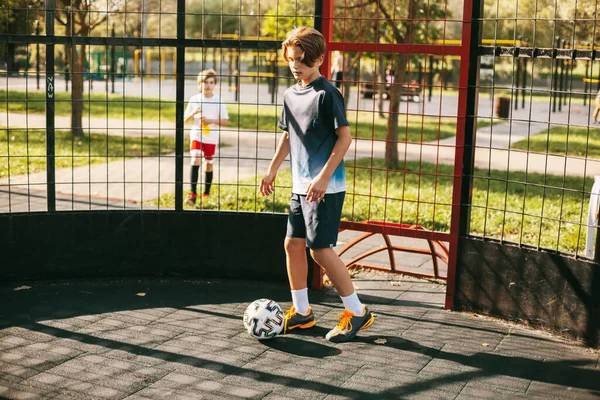 Seorang pemuda berseragam olahraga berlatih dengan bola di lapangan sepak bola gaya bebas. Seorang pemain sepak bola bermain dengan bola. Olahraga, rekreasi, pelatihan, gaya bebas — Stok Foto