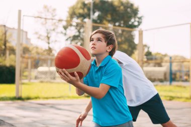 İki genç çocuk oyun sahasında basketbol oynuyor. Sporcular maçta top için savaşırlar. Sağlıklı yaşam tarzı, spor, motivasyon
