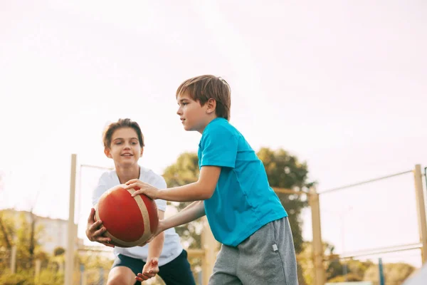 십 대 소년 두 명이 운동장에서 농구를 한다. 선수들은 경기중에 공을 놓고 싸웁니다. 건강 한 생활, 스포츠, 동기 — 스톡 사진