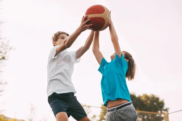 İki genç çocuk oyun sahasında basketbol oynuyor. Sporcular maçta top için savaşırlar. Sağlıklı yaşam tarzı, spor