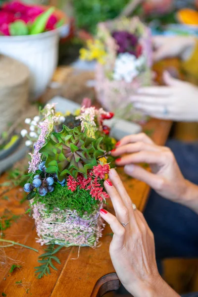 Female hands making beautiful bouquet of flowers on background. hands correcting flowers in the composition on the table