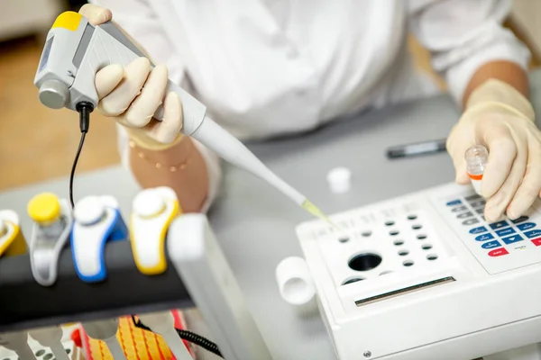 Ο Βοηθός εργαστηρίου τοποθετεί ένα δείγμα αίματος για ανάλυση σε μια πρόσθετη συσκευή, γκρο πλαν — Φωτογραφία Αρχείου