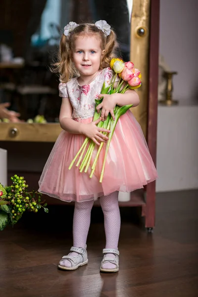 Blue-eyed Ładna dziewczyna w różowej sukience, trzymając w dłoniach naręczem tulipany — Zdjęcie stockowe