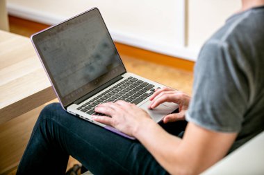 Genç adam gözlüklü bir ev ofis içinde bir laptop üzerinde yoğunlaşmıştır. Metin, yakın çekim düzeltir. yatay çekim