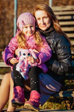 Güneşli bir sonbahar gününde bir yolda kızıyla birlikte genç güzel anne. portre