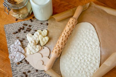 Oklava ile dekore edilmiş ahşap bir masa üzerinde bir desen ile pişmiş un kaplı. Bir desen ve bir kalp şeklinde çerez ile rulo hamur. Aşk şarkısı. Arka plan, yakın çekim yemek bisküvi.