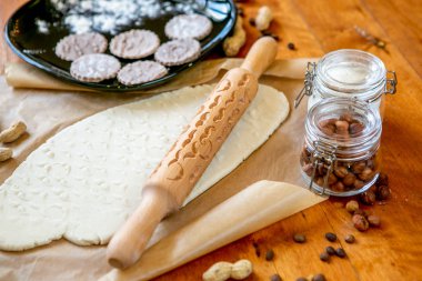 Oklava dekore edilmiş ahşap bir masa üzerinde bir bıyık desenli pişmiş un ile kaplı. Bir desen ve çerez çeşitli şekiller ile rulo hamur. Arka plan, yakın çekim yemek bisküvi.