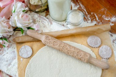 Oklava ile dekore edilmiş ahşap bir masa üzerinde bir desen ile pişmiş un kaplı. Bir desen ve çerez çeşitli şekiller ile rulo hamur. Arka plan, yakın çekim yemek bisküvi.