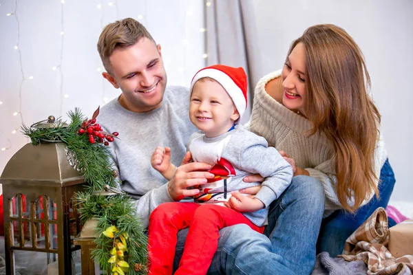 Happy family, father, mother and son, in the morning in bedroom decorated for Christmas. They open presents and have fun. New Year\'s and Christmas theme. Holiday mood.