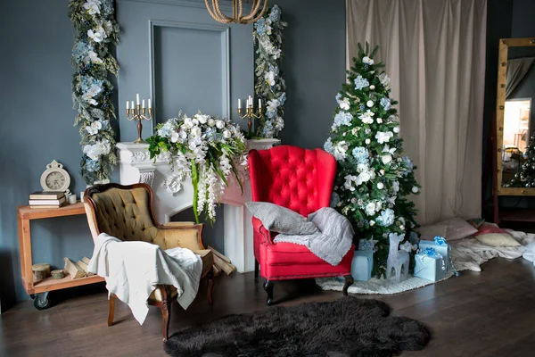Loft tarzı oda kırmızı ve kahverengi koltuk, çiçekli, beyaz bir şömine ile Noel için dekore edilmiştir. Noel ağacı, hediyeler. Noel sabahı. Tatil ruh hali
