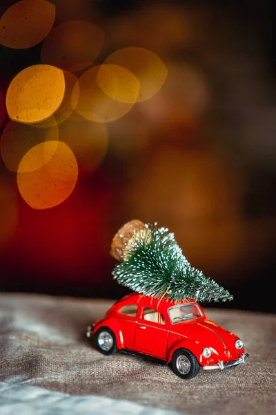 Juguete de coche rojo con abeto en su techo en lámparas de guirnalda fondo bokeh, primer plano. Humor de vacaciones. Feliz Año Nuevo y Navidad tema. Tarjeta de Navidad —  Fotos de Stock