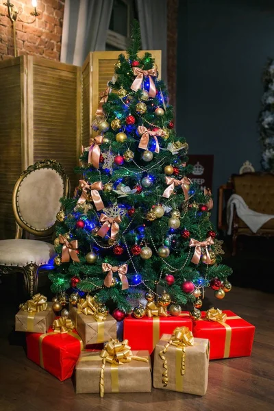 Árbol de Navidad brillante decorado con bolas y arcos, con regalos debajo de él en la sala de estar de estilo loft. Noche de Navidad. Humor de vacaciones —  Fotos de Stock