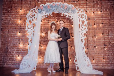 Mutlu genç gelin ve damat bir klasik iç çiçeklerle düğün arch yakınındaki portresi. Düğün günü, aşk şarkısı. Yeni bir aile ilk günü