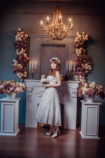 Портрет счастливой молодой невесты в классическом интерьере у камина с цветами. День свадьбы, тема любви. Первый день в новой семье — стоковое фото