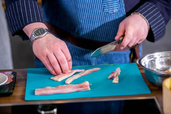 Chef cuts fish into pieces. Master class in the kitchen. The process of cooking. Step by step. Tutorial. Close-up