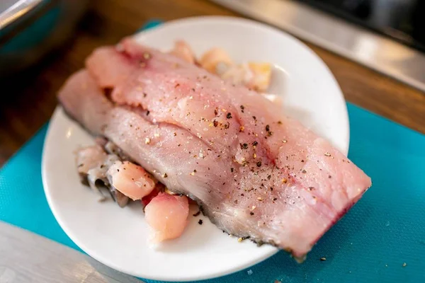 Morceau de poisson cru avec des épices sur une assiette. Cours de maître dans la cuisine. Le processus de cuisson. Pas à pas. Tutoriel. Gros plan — Photo
