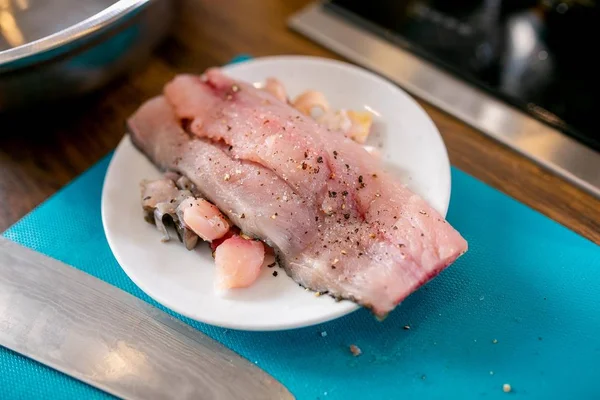 Morceau de poisson cru avec des épices sur une assiette. Cours de maître dans la cuisine. Le processus de cuisson. Pas à pas. Tutoriel. Gros plan — Photo