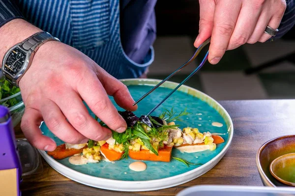 Chef decorates the salad with smoked catfish, carrots and miso sause. Master class in the kitchen. The process of cooking. Step by step. Tutorial. Close-up