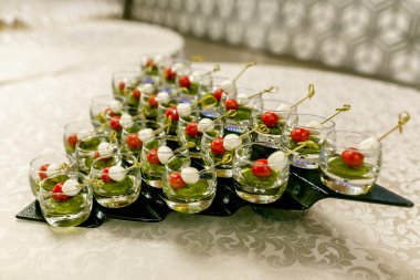 resepsiyondaki büfe. Arka planda şarap ve şampanya kadehleri. Cam bardaklarda kanepe çeşitleri. Ziyafet servisi. Catering gıda, peynir ve küçük domates ile aperatifler