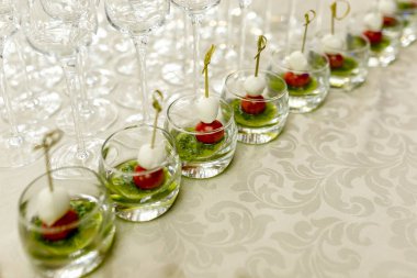 resepsiyondaki büfe. Arka planda şarap ve şampanya kadehleri. Cam bardaklarda kanepe çeşitleri. Ziyafet servisi. Catering gıda, peynir ve küçük domates ile aperatifler