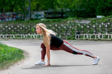 Fitness yaşam tarzı. Genç kadın yan hamle yapıyor. Stadyumda antrenman. Sağlıklı yaşam kavramı. Yatay fotoğraf