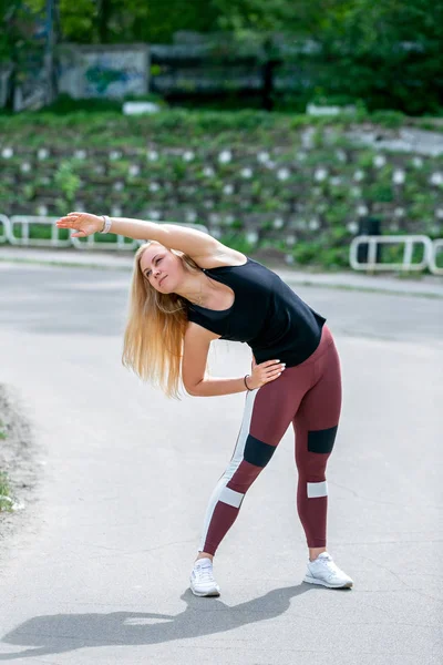 Styl życia fitness. Młoda kobieta Rozgrzewka przed treningiem robi ćwiczenia, aby rozciągnąć jej mięśnie i stawy. Trening na stadionie. Koncepcja zdrowego życia — Zdjęcie stockowe