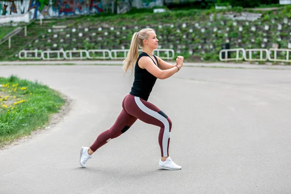 Estilo de vida fitness. Jovem mulher fazendo lunges em um salto. Treino no estádio. Conceito de vida saudável — Fotografia de Stock
