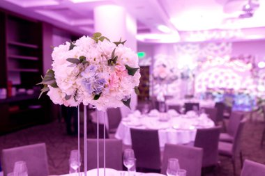 Bir parti, düğün resepsiyon veya diğer festival olay için yüksek bir kök üzerinde bir vazo tabak ve beyaz çiçek düzenlemeleri ile güzel masa ayarı. Catered etkinlik yemeği için cam eşya ve çatal bıçak takımı