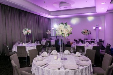 Bir parti, düğün resepsiyon veya diğer festival olay için yüksek bir kök üzerinde bir vazo tabak ve beyaz çiçek düzenlemeleri ile güzel masa ayarı. Catered etkinlik yemeği için cam eşya ve çatal bıçak takımı