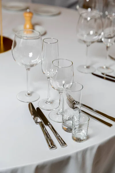 Beautiful table setting with crockery for a party, wedding reception or other festive event. Empty glassware and cutlery for catered event dinner. Vertical photo