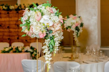 Bir parti, düğün resepsiyon veya diğer festival olay için yüksek bir kök üzerinde bir vazo tabak ve beyaz çiçek düzenlemeleri ile güzel masa ayarı. Catered etkinlik yemeği için cam eşya ve çatal bıçak takımı