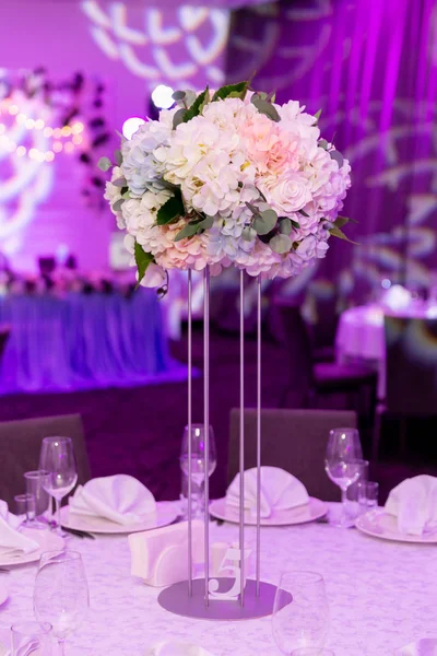 Hermosa mesa con vajilla y arreglo de flores blancas en un jarrón en un tallo alto para una fiesta, recepción de boda u otro evento festivo. Vajilla y cubiertos para la cena del evento abastecido — Foto de Stock