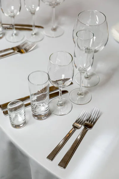 Beautiful table setting with crockery for a party, wedding reception or other festive event. Glassware and cutlery for catered event dinner. Vertical photo