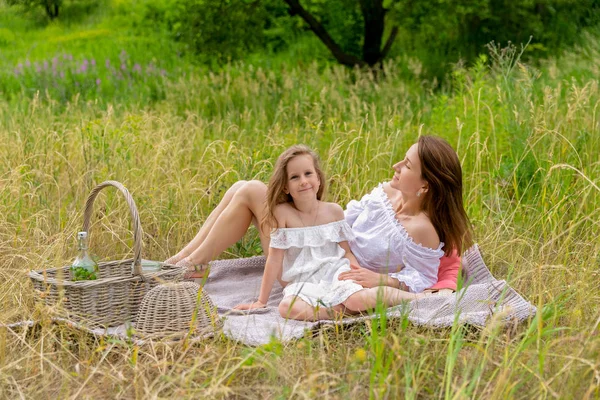 Красива молода мати і її маленька дочка в білій сукні розважаються на пікніку. Догляд за дітьми та кохання. Горизонтальна фотографія — стокове фото