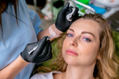 Beautician kadın yüzüne botulinum toksin enjekte etmeye hazırlanıyor. Kozmetolojik prosedürlerde genç bir kadın. Close. Güzellik ve sağlıklı yaşam. Yatay fotoğraf