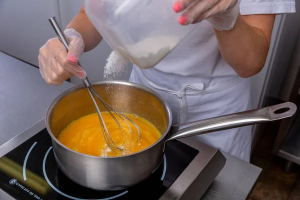 Pastry chef in the kitchen makes passion fruit confit. Cook mixes the fruits in a saucepan and adds sugar. Master class in the kitchen. The process of cooking. Step by step. Tutorial. Close-up