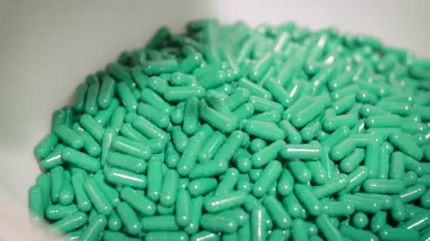 Pastillas de cápsulas verdes cayendo en el tazón blanco del colector de polvo farmacéutico — Vídeos de Stock