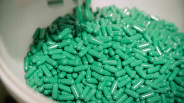 Зелені таблетки капсули падають у білій мисці — стокове відео