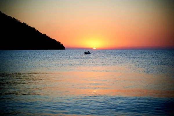 Denizin üstünde turuncu gün batımı ve sakin dalgalarda güneşin altın yansıması. — Stok fotoğraf