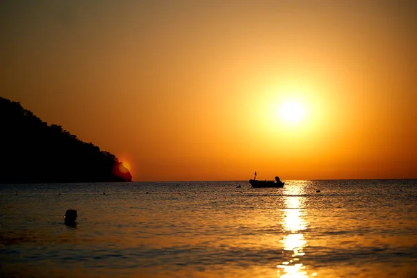 Помаранчевий захід сонця над морем з човном дивовижне золоте відображення сонця на спокійних хвилях — стокове фото