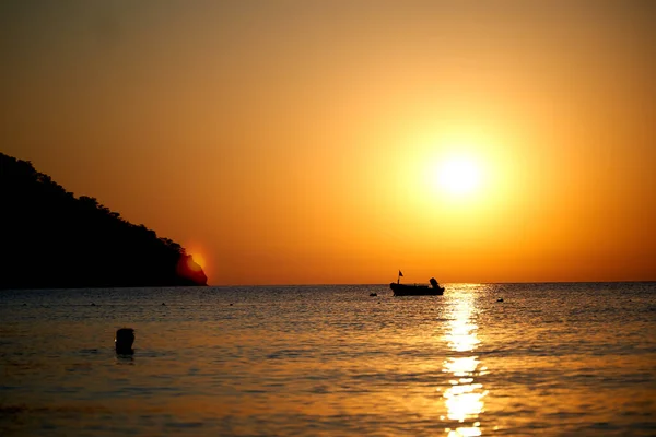 Помаранчевий захід сонця над морем з човном дивовижне золоте відображення сонця на спокійних хвилях — стокове фото