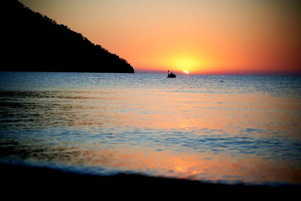 Naranja puesta de sol sobre el mar con barco increíble reflejo dorado del sol en las olas tranquilas —  Fotos de Stock