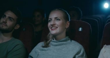 Çekici, gülümseyen genç kadının arkadaşları ile komik bir film izlerken bir sinema oturan yakın çekim.